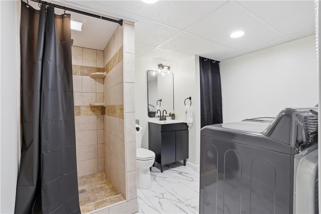 2918 Keystone Street Bethlehem, PA 18020 - Photo 27 of 54 A compact and efficient space featuring a tiled shower stall, modern vanity, and integrated laundry appliances.