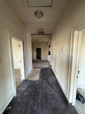 a view of a hallway to a bedroom with wooden floor and stairs