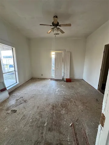en empty room with windows and ceiling fan