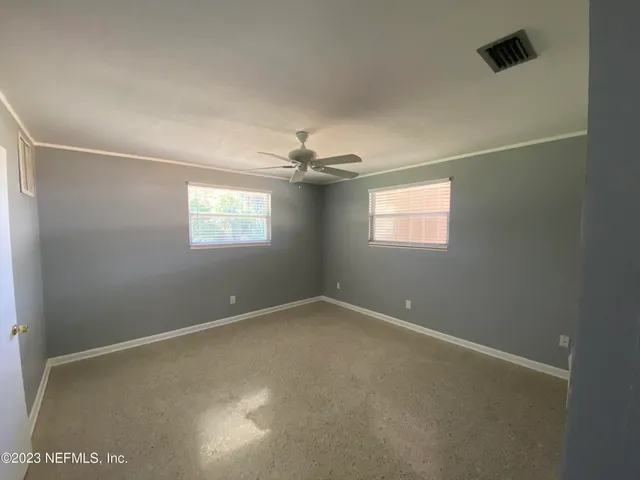 an empty room with windows and chandelier fan