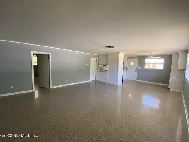 an empty room with windows and chandelier fan