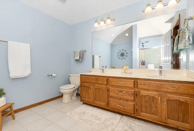 a bathroom with a granite countertop double vanity sink a mirror and a toilet