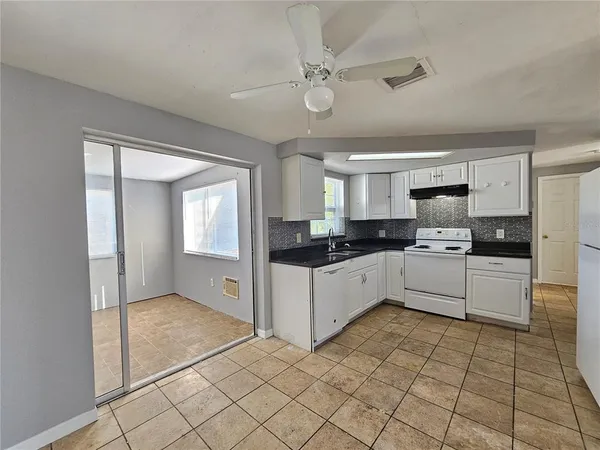 a large white kitchen with a refrigerator a stove top oven and a sink