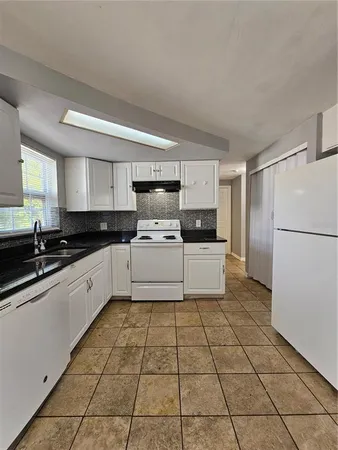 a kitchen with a sink a stove a refrigerator and cabinets