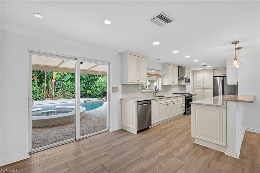 1135 7th Street South Naples, FL 34102 - Photo 12 of 35 a kitchen with white cabinets and wooden floor