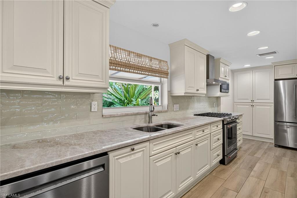 1135 7th Street South Naples, FL 34102 - Photo 14 of 35 a kitchen with stainless steel appliances granite countertop a sink a stove a refrigerator and cabinets