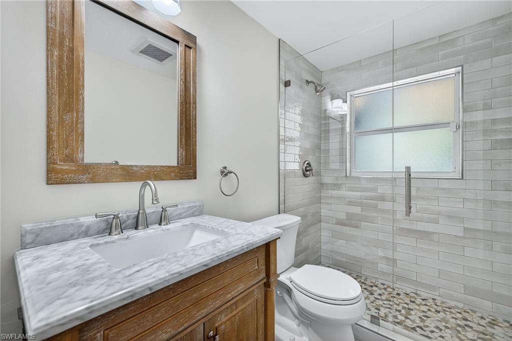 1135 7th Street South Naples, FL 34102 - Photo 27 of 35 a bathroom with a granite countertop sink a toilet and a mirror