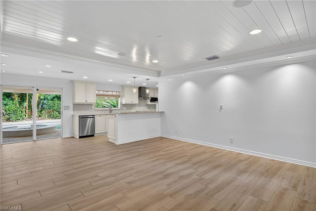 1135 7th Street South Naples, FL 34102 - Photo 8 of 35 a view of a kitchen with kitchen island a sink wooden floor and a refrigerator