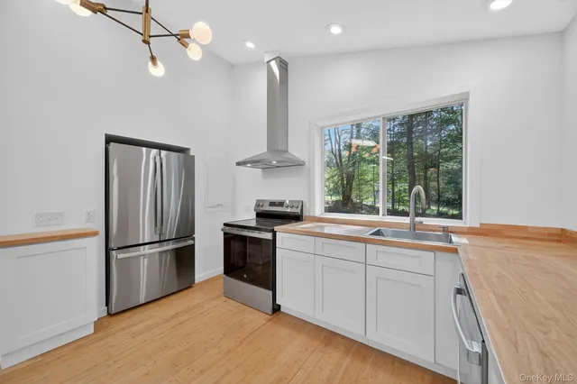 a kitchen with stainless steel appliances granite countertop a sink a stove a refrigerator and island with wooden floor