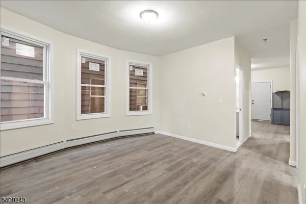 a view of an empty room with a window and wooden floor