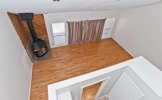 a view of empty room with wooden floor and a window