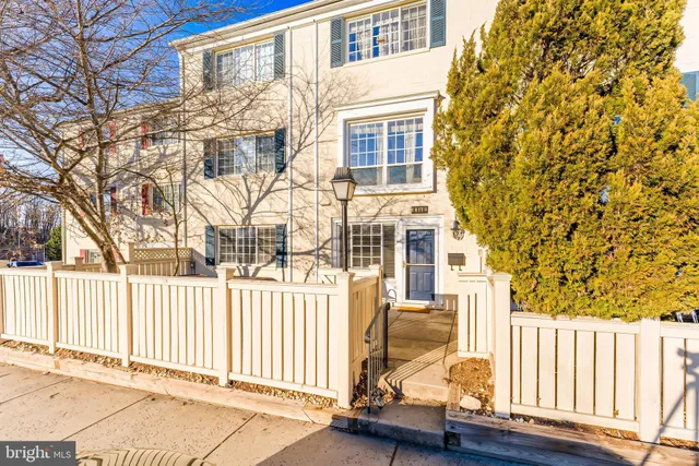 a view of a brick house with a large window and wooden fence