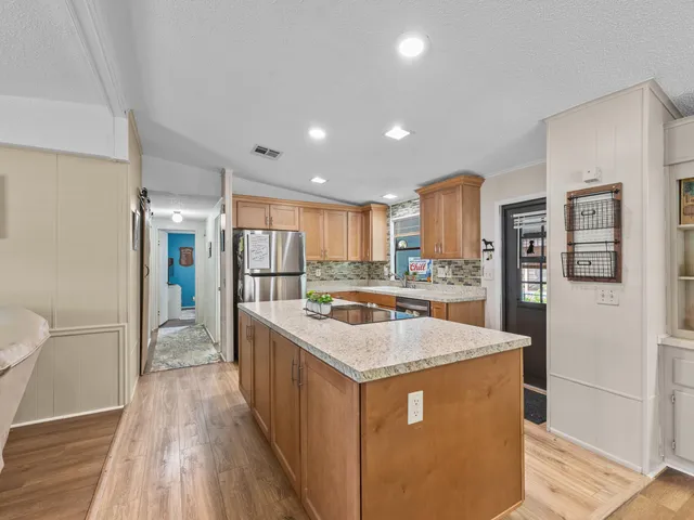 a kitchen with stainless steel appliances granite countertop a refrigerator a sink dishwasher and a stove with wooden floor