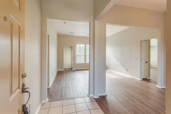 a view of a hallway with wooden floor and a bathroom
