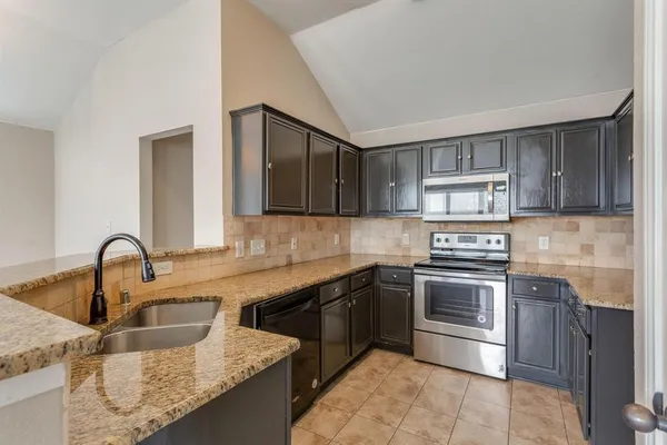a kitchen with stainless steel appliances granite countertop a sink stove and cabinets