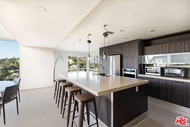 a kitchen with stainless steel appliances granite countertop a table chairs stove and refrigerator
