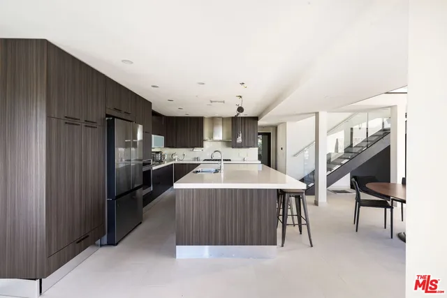 a kitchen with stainless steel appliances kitchen island granite countertop a refrigerator and a stove top oven