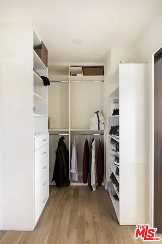 a view of walk in closet with clothes and shoes