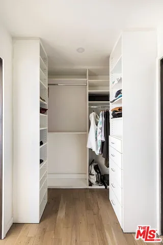 a view of walk in closet with clothes and shoes