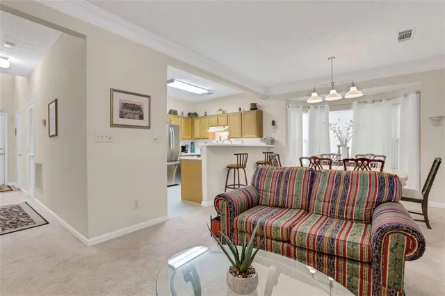 a living room with furniture kitchen view and a chandelier