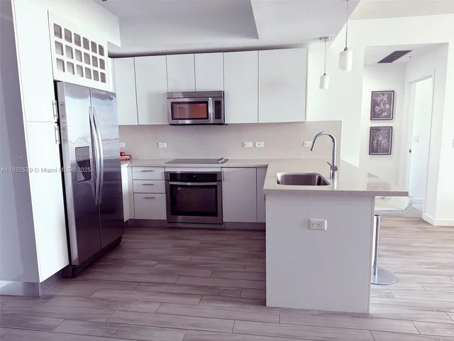 a kitchen with kitchen island granite countertop a sink cabinets and wooden floor