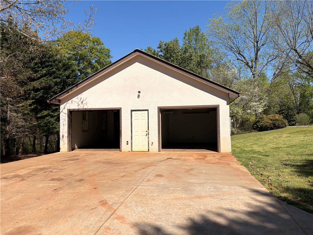 703 Burnt Tanyard Road Salem, SC 29676 - Photo 33 of 41 This functional garage offers ample space for vehicles and storage, blending seamlessly with its natural surroundings.