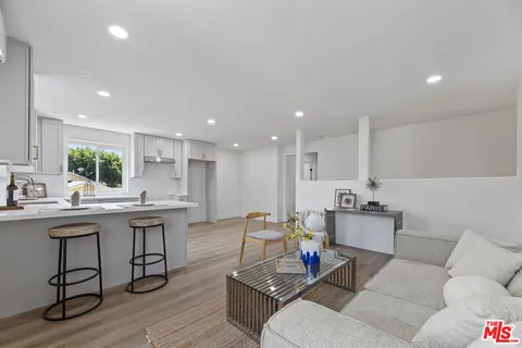 a living room with furniture kitchen view and a wooden floor