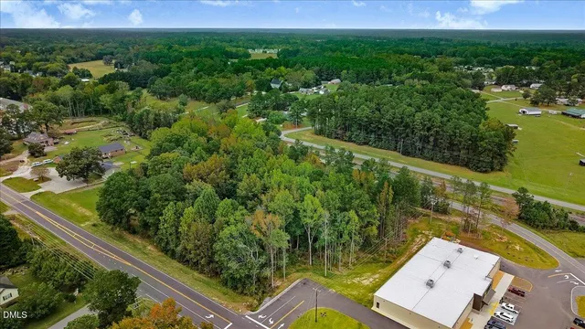 an aerial view of a residential houses with outdoor space and trees all around