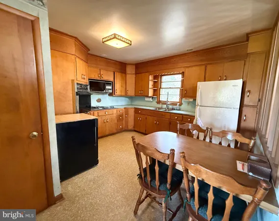 a kitchen with kitchen island a dining table chairs and a refrigerator