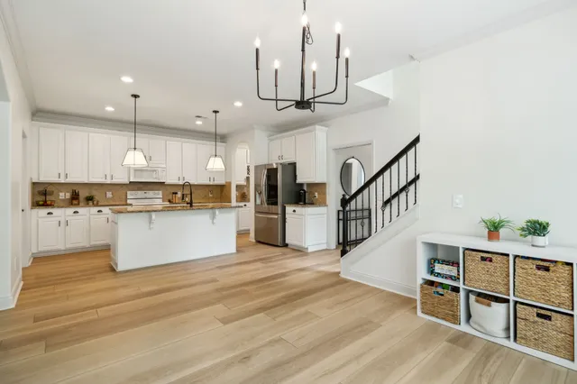 a large kitchen with stainless steel appliances kitchen island granite countertop a wooden floor and cabinets
