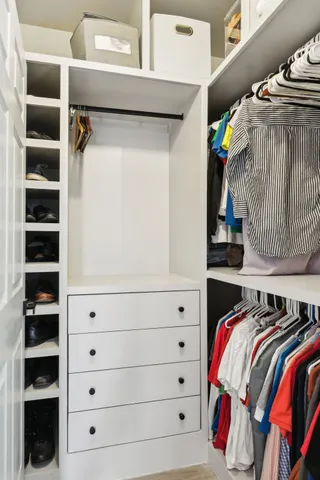 a view of walk in closet with clothes and shoes