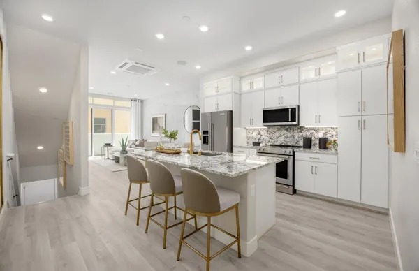 a kitchen with microwave a refrigerator and chairs
