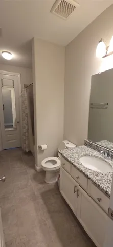 a bathroom with a granite countertop sink a toilet and mirror