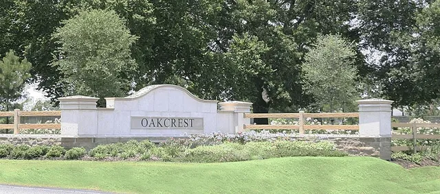 a sign that is sitting in front of a big tree with wooden fence