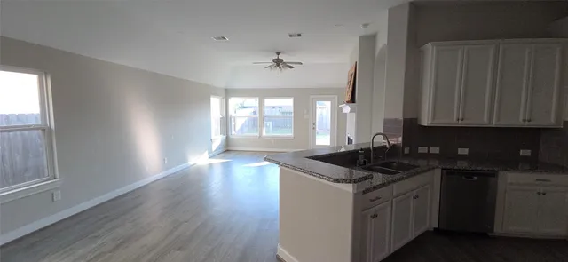 a kitchen with granite countertop a sink stove and cabinets
