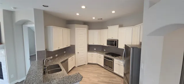 a kitchen with stainless steel appliances granite countertop a stove a sink and a refrigerator