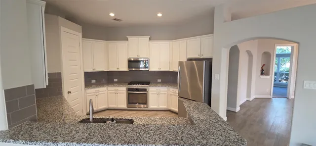 a kitchen with stainless steel appliances granite countertop a refrigerator and a sink