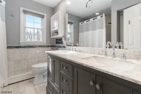 a bathroom with a granite countertop sink a toilet and a mirror