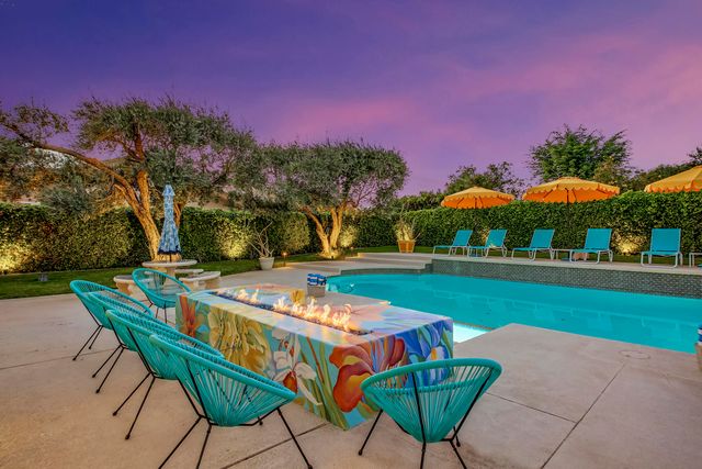 a view of a swimming pool with a lawn chairs and a fire pit