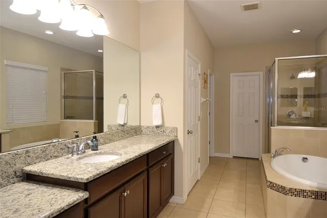a bathroom with a granite countertop double vanity sink and a bathtub