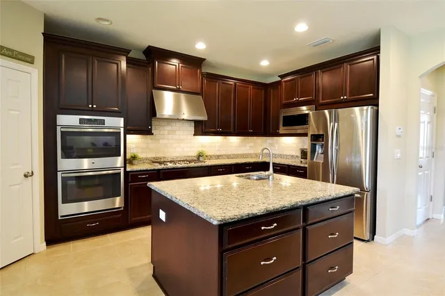 a kitchen with a refrigerator sink and cabinets