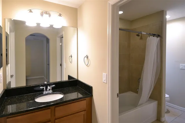 a bathroom with a granite countertop sink a mirror and shower