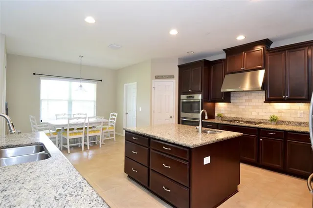 a kitchen with a stove a sink a oven a dining table and chairs