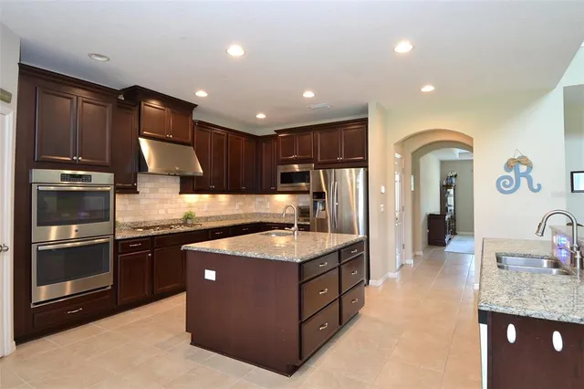 a kitchen with kitchen island granite countertop stainless steel appliances a sink stove and refrigerator