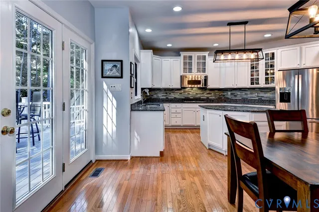 a kitchen with stainless steel appliances granite countertop a refrigerator a stove and a wooden floors