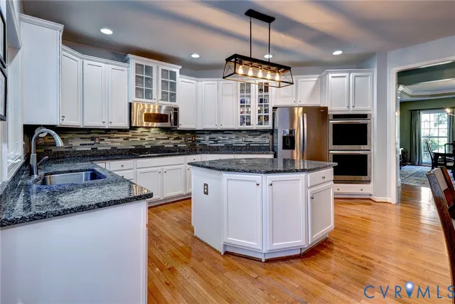 a kitchen with stainless steel appliances granite countertop a sink a stove a refrigerator a center island and cabinets
