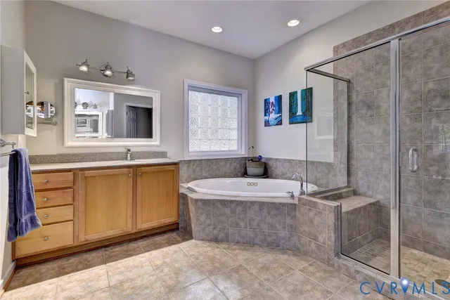 a spacious bathroom with a granite countertop sink a mirror a bathtub and shower