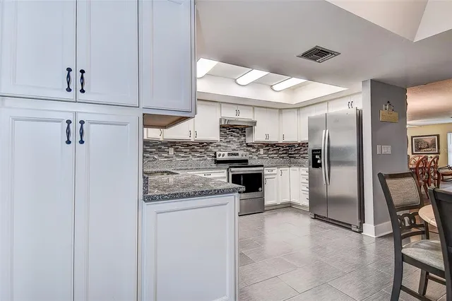 a kitchen with granite countertop white cabinets and white appliances