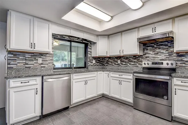 a kitchen with stainless steel appliances granite countertop a sink a stove a refrigerator and cabinets