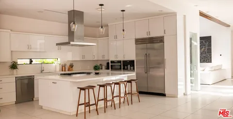 a kitchen with stainless steel appliances granite countertop a sink a stove a refrigerator and island